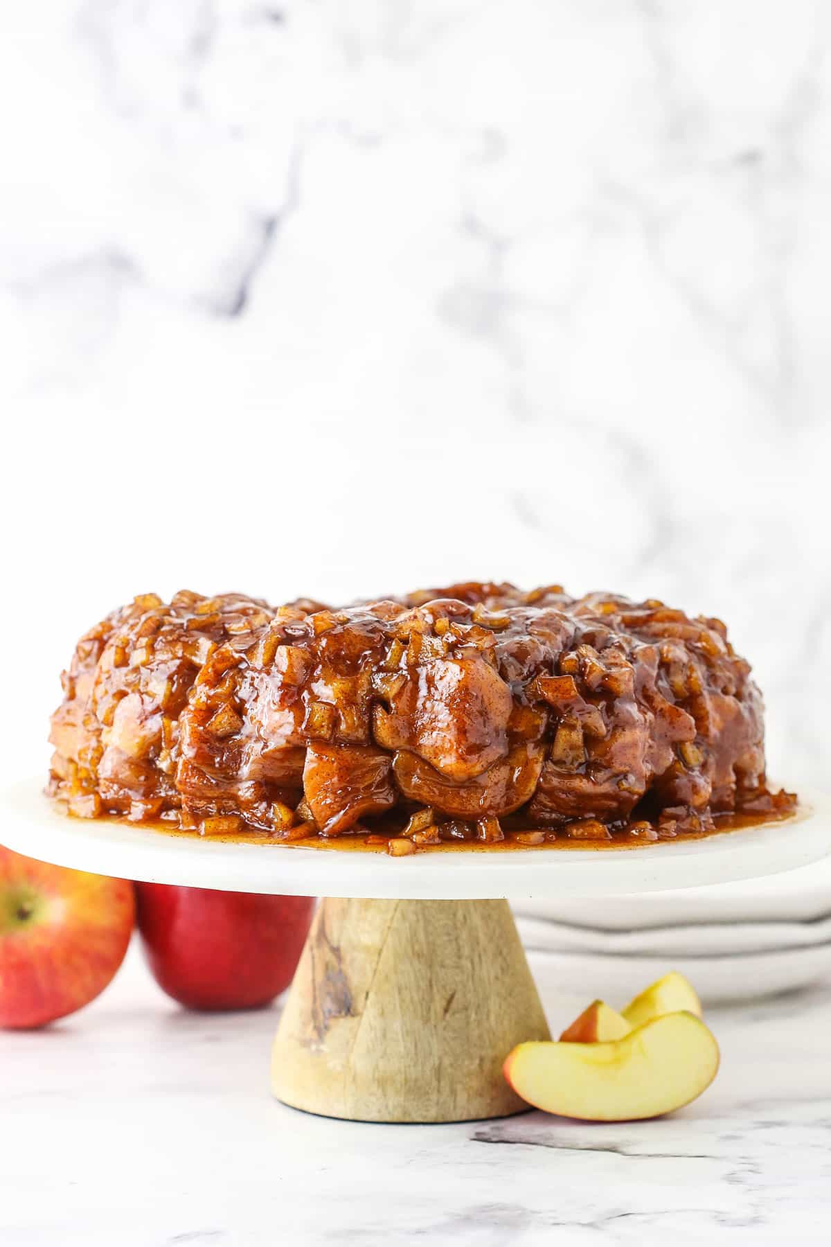 Side view of Apple Fritter Monkey Bread on a white cake stand