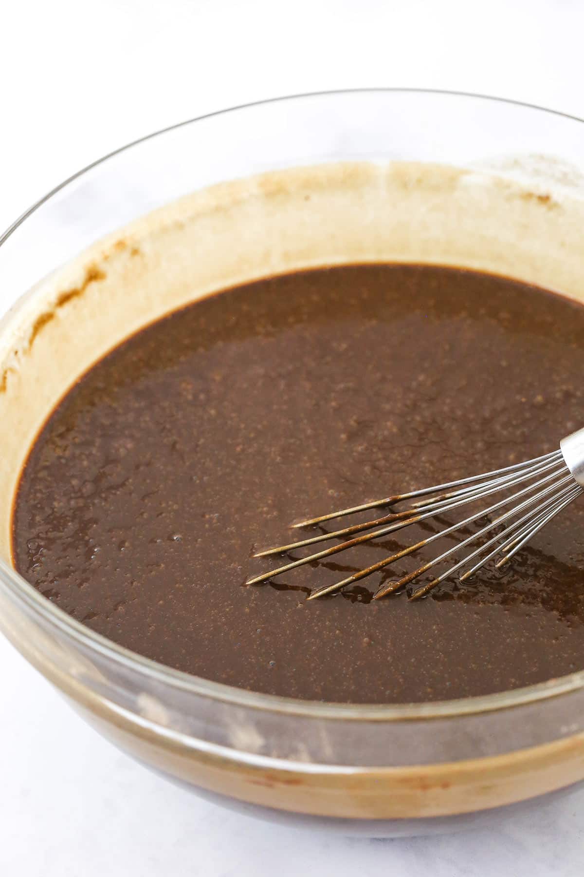 Chocolate cake batter in a glass bowl with a whisk