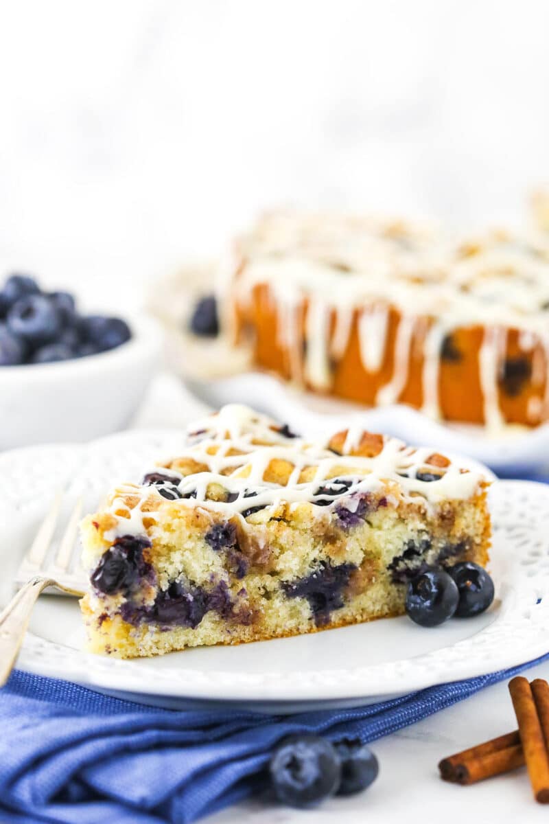 slice of blueberry streusel coffee cake on white plate and blue napkin