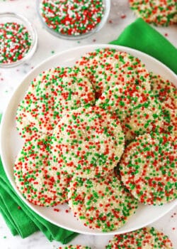 A plate piled high with sugar cookies coated in red, white and green nonpareil sprinkles