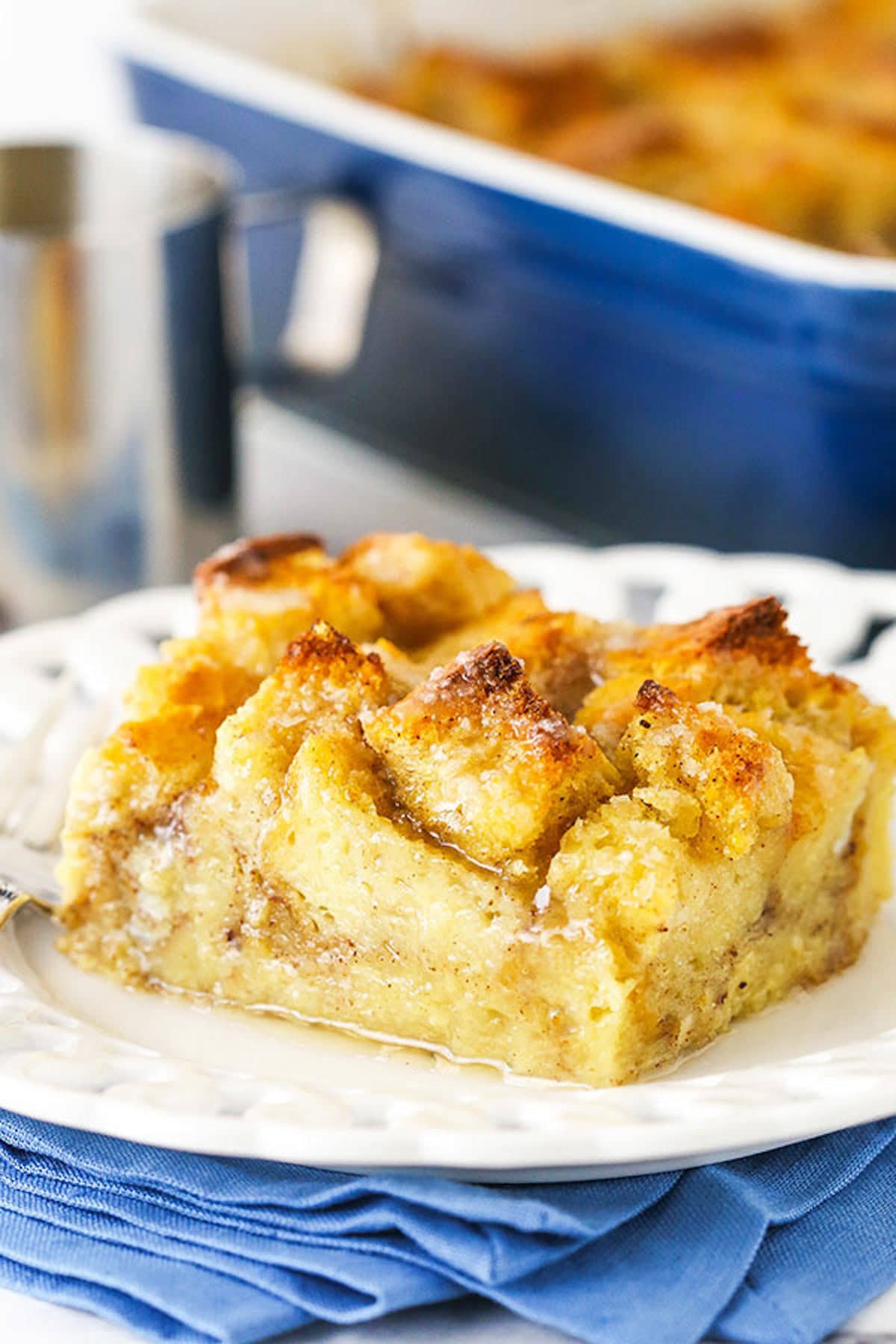 A single serving of bread pudding sitting on a plate on top of a blue napkin. 