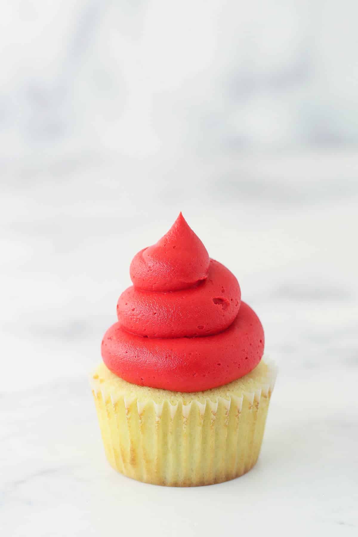 red frosting piped onto cupcake for santa hat
