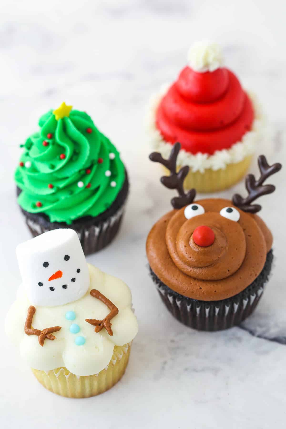 one of each of the 4 christmas cupcakes designs on a marble background