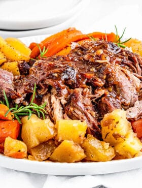 Shredded instant pot pork roast on a platter with potatoes and carrots