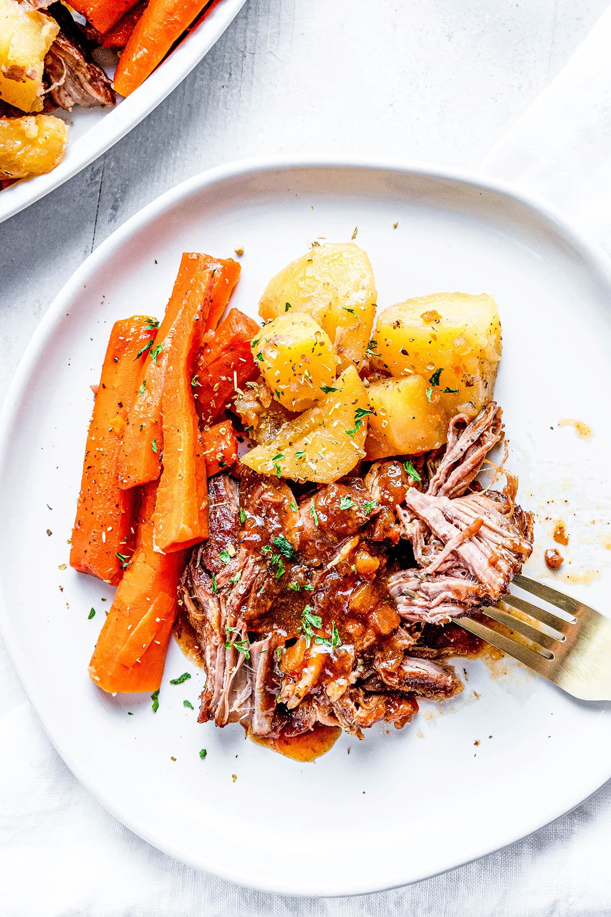 Instant pot pork roast with carrots and potatoes on a white plate
