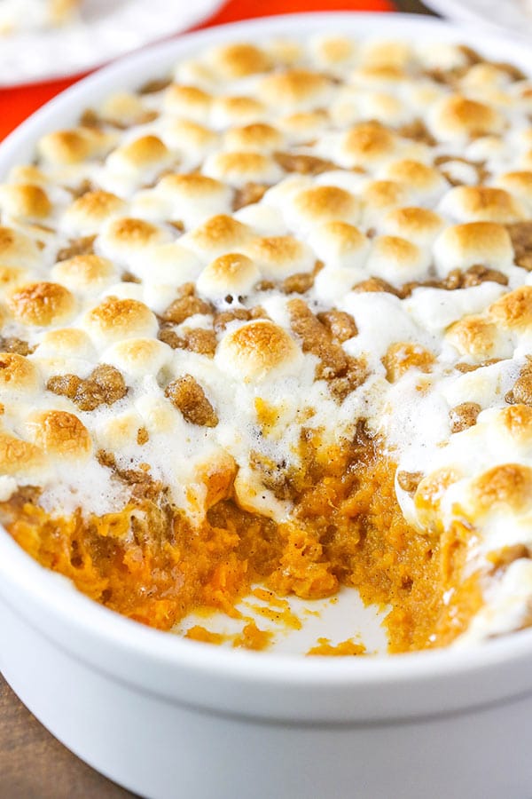 Close up of Sweet Potato Casserole with marshmallows on top and a serving missing
