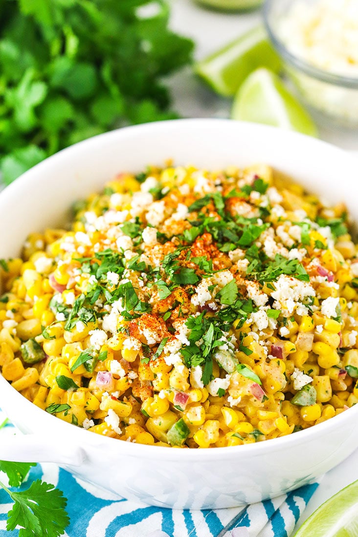mexican street corn salad in white bowl on teal and white napkin