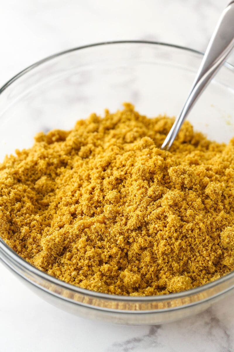 Mixing together butter, sugar, and graham cracker crumbs for graham cracker crust.