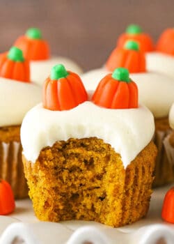 A frosted pumpkin cupcake on a serving platter with a big bite taken out of it