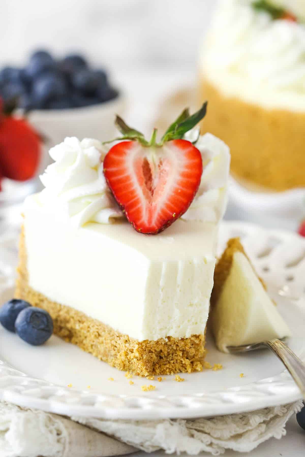 A slice of no bake cheesecake on a plate with a bite taken out of it.