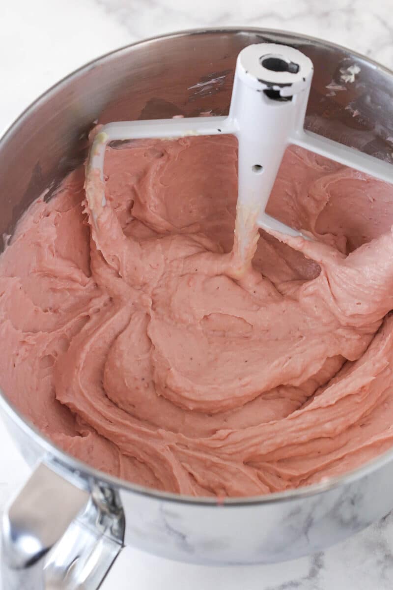 Beating strawberry mixture into a cream cheese and sugar mixture.