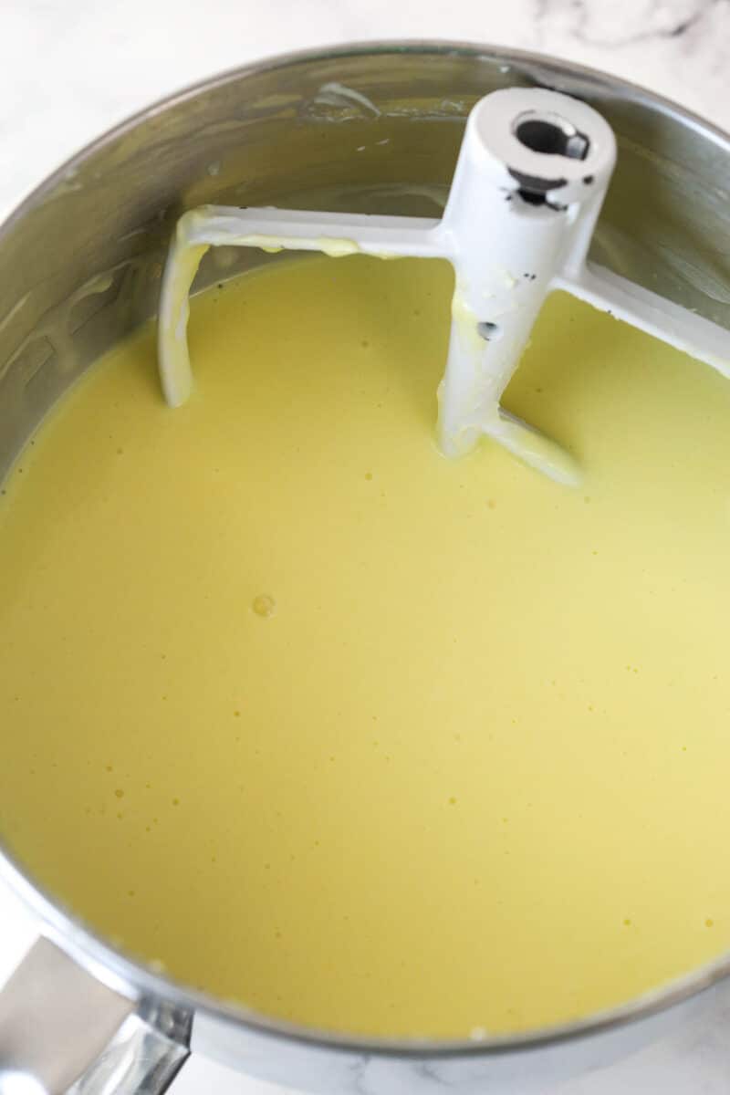 Adding eggs and egg yolks to cheesecake filling.