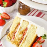 slice of Strawberry Dulce De Leche Cake with strawberries and dulce de leche in background