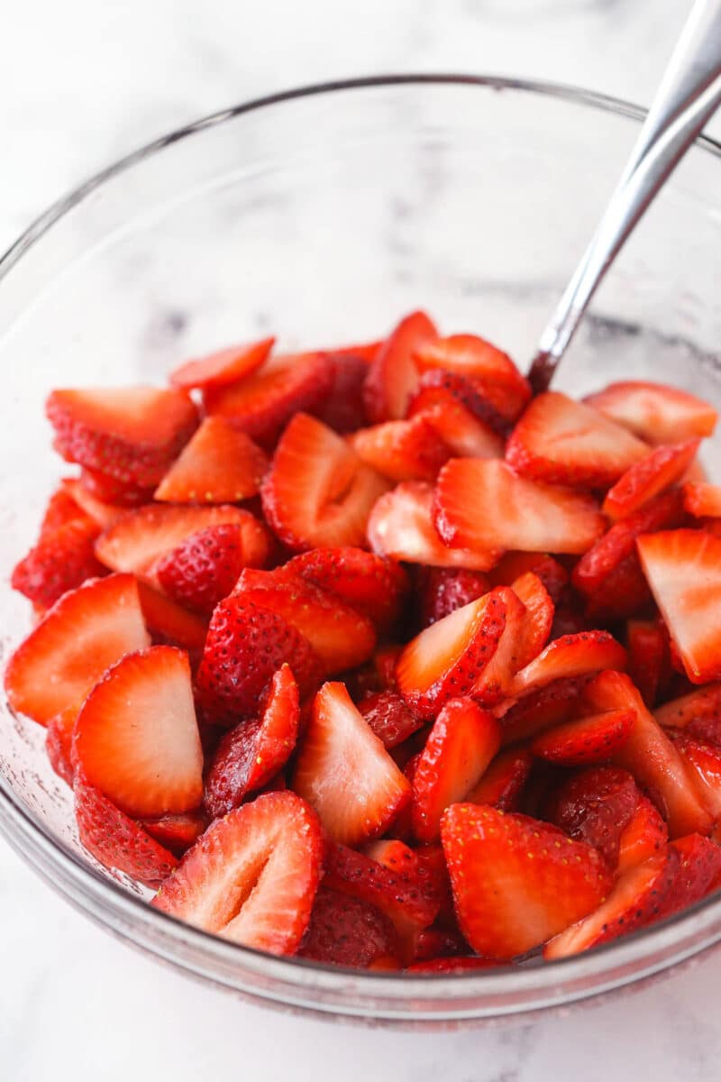 Sliced strawberries coated in sugar in a bowl.