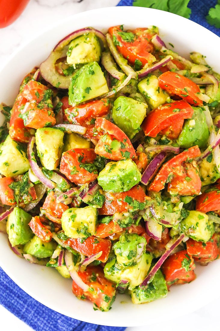 Tomatoes, avocados, and onion mixed together in a bowl