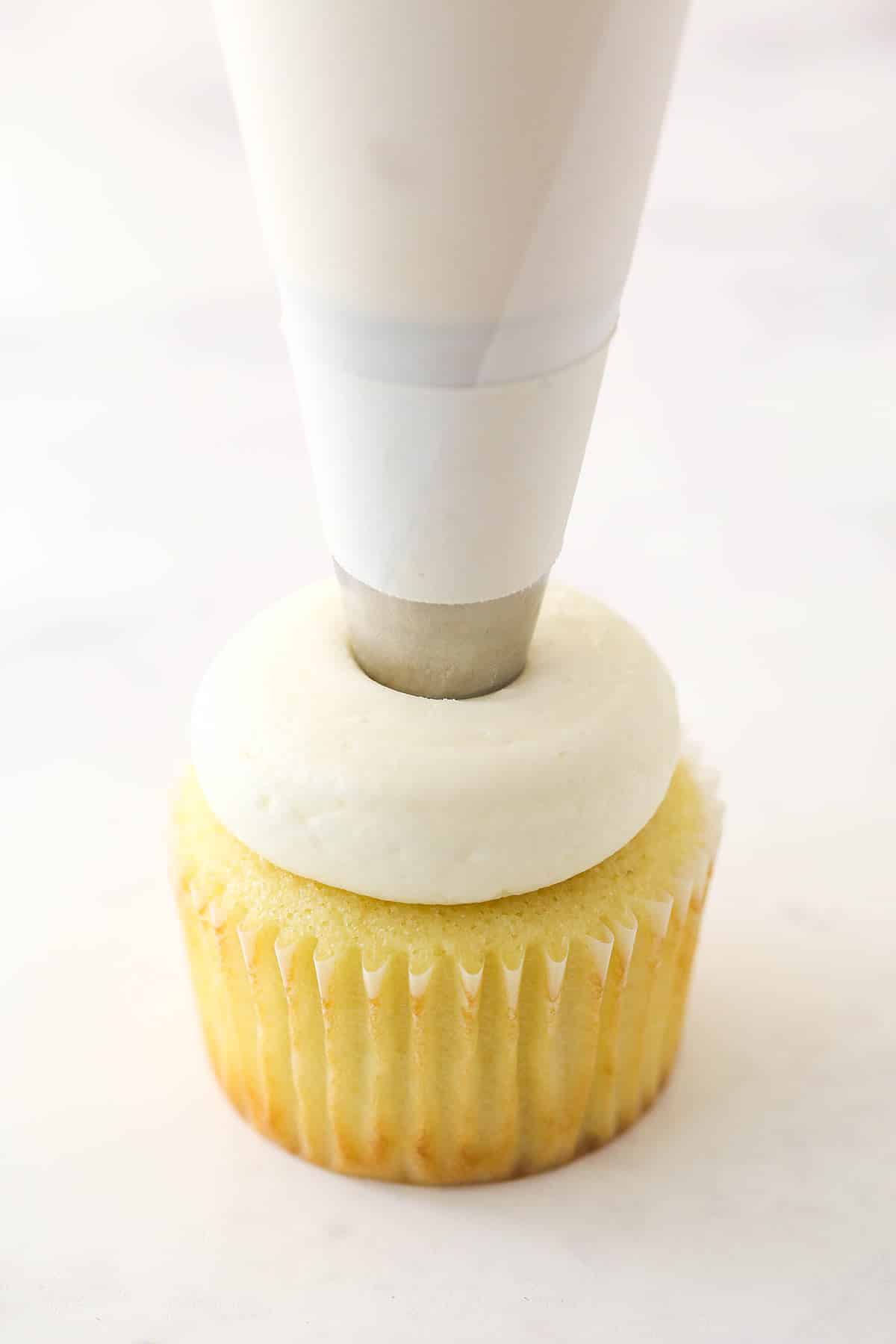 Piping the buttercream on a vanilla cupcake.